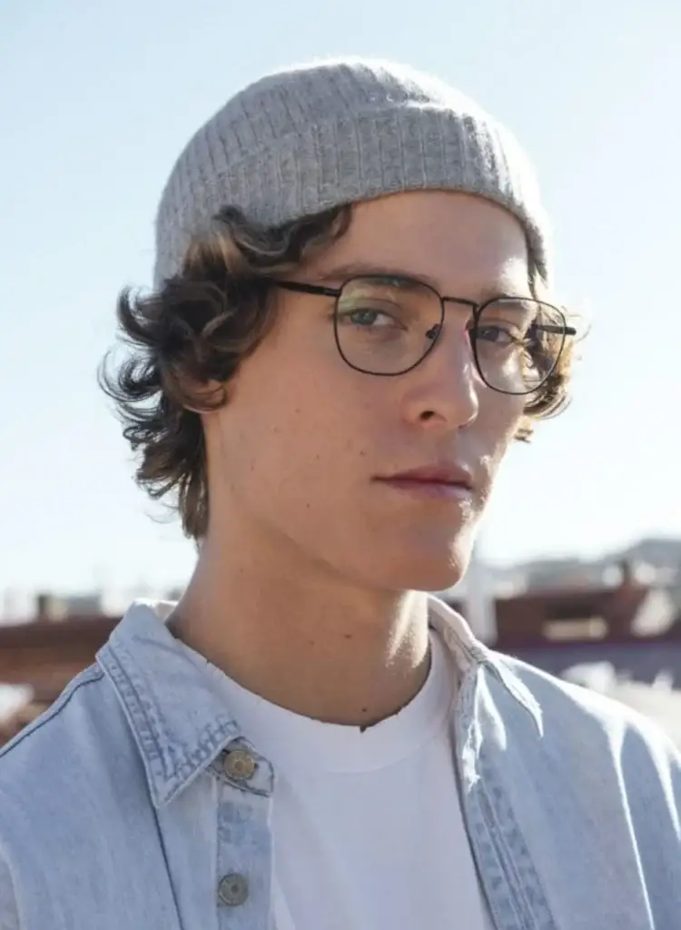 Joven con gafas de montura delgada en exterior bajo luz natural – Óptica Newton Bogotá