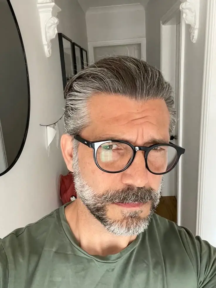 Hombre con gafas de montura negra de estilo clásico en interior de vivienda – Óptica Newton Bogotá