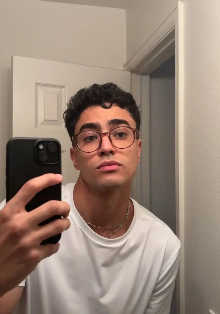 Joven con gafas de montura redonda tomándose una selfie en espejo – Óptica Newton Bogotá