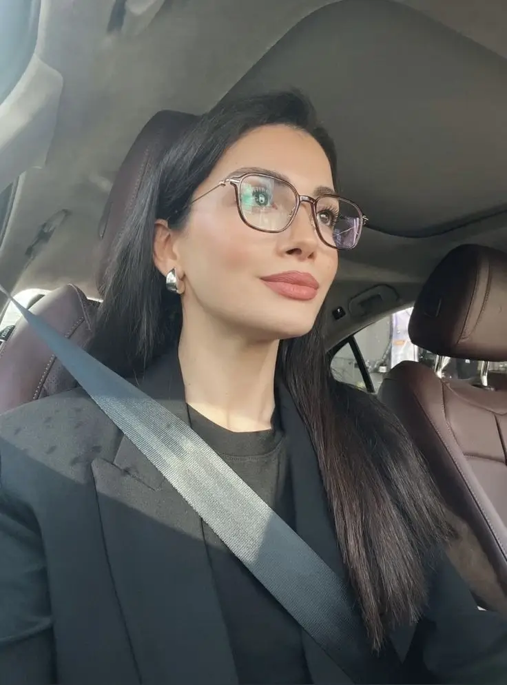 Mujer usando gafas de montura transparente mientras conduce, mostrando lentes de Óptica Newton en Bogotá.