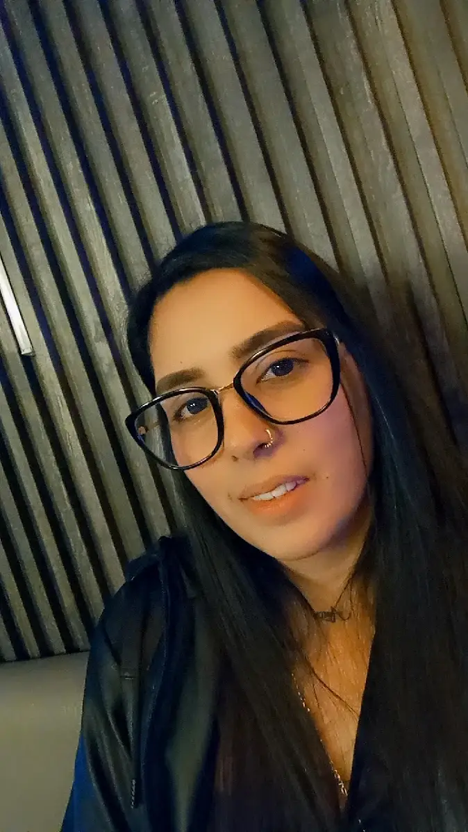 Mujer usando gafas de montura negra rectangular en un ambiente interior, mostrando estilos disponibles en Óptica Newton Bogotá.