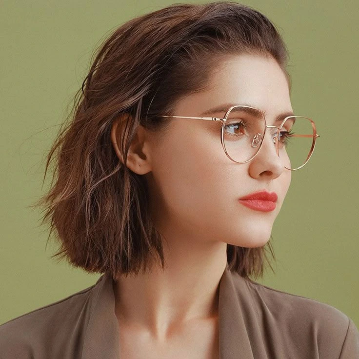 Mujer con gafas de montura redonda dorada mirando hacia un lado – Óptica Newton Bogotá